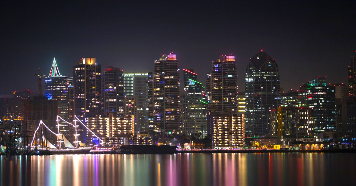 Stunning view of San Diego's illuminated skyline reflecting in calm waters at night.